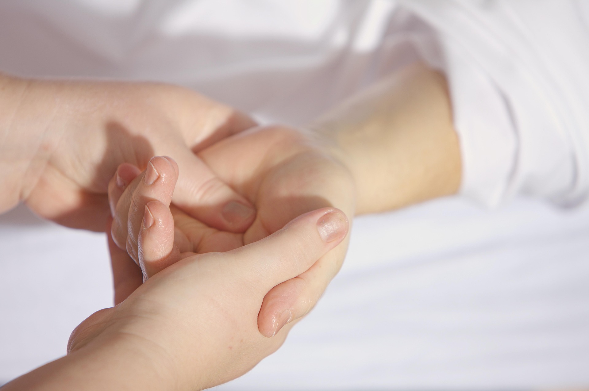 Close-up of a therapist's hands applying pressure to a person's upper back during a massage